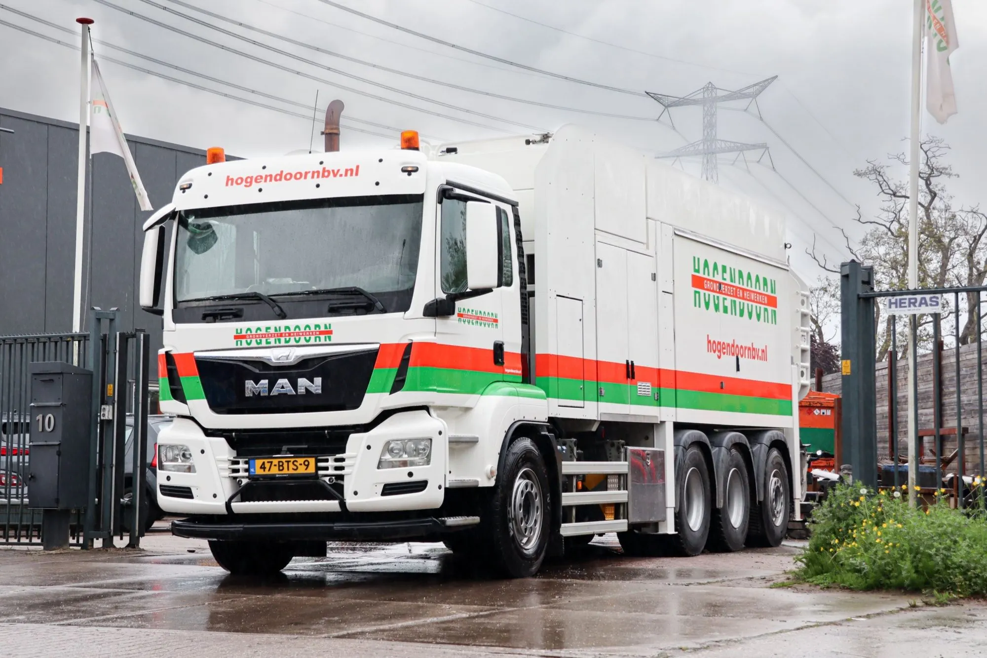 MAN grondzuigauto in Hogendoorn-belettering bij de poort van het pand