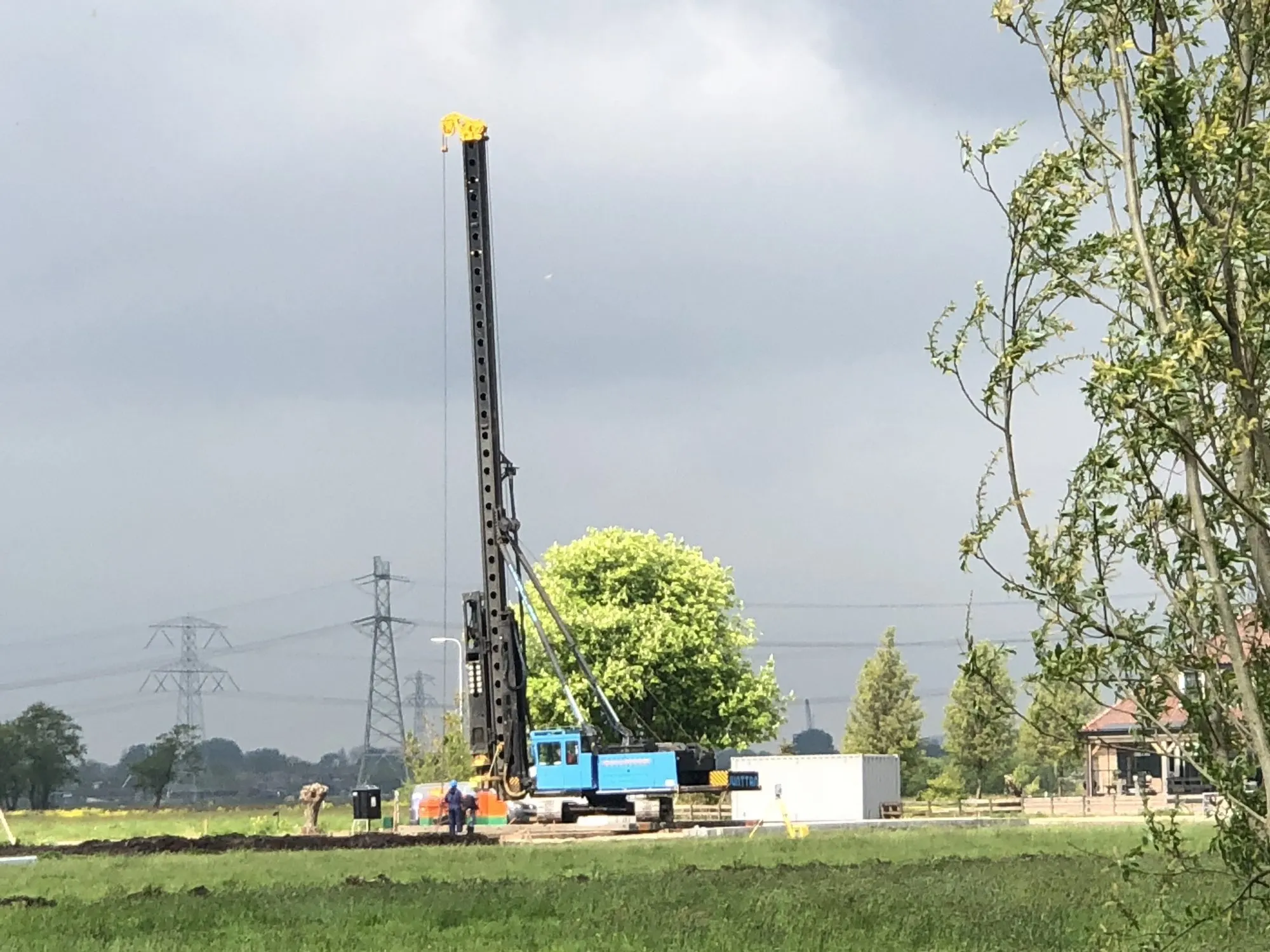 Heistelling in een weiland, hoogspanningsmasten op de achtergrond