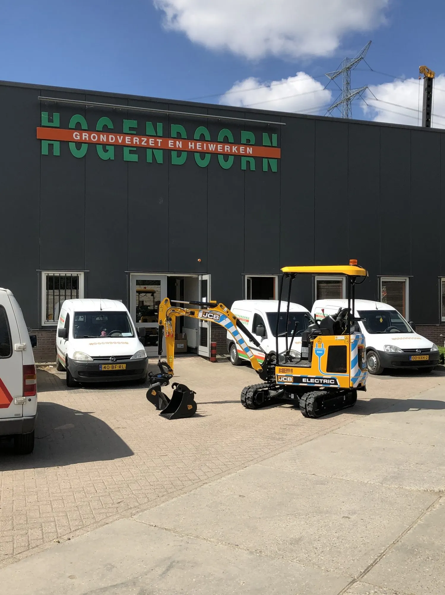 Elektrische JCB 19C minigraver voor het pand van Hogendoorn