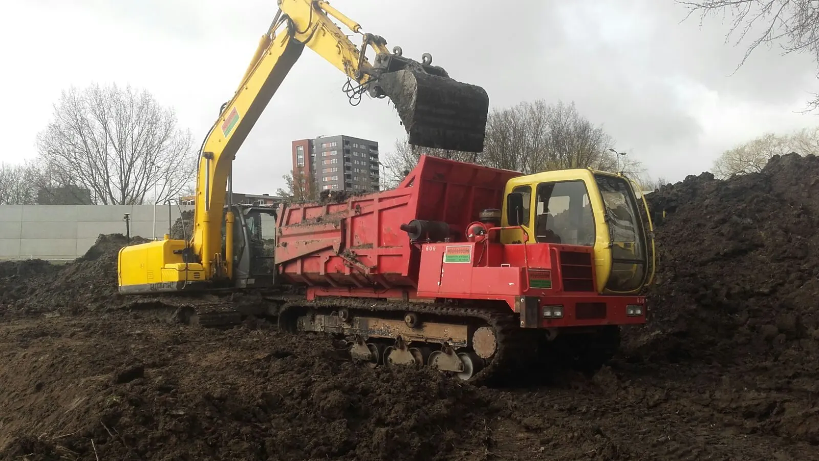 Rode Morooka rupsdumper wordt geladen door een rupskraan