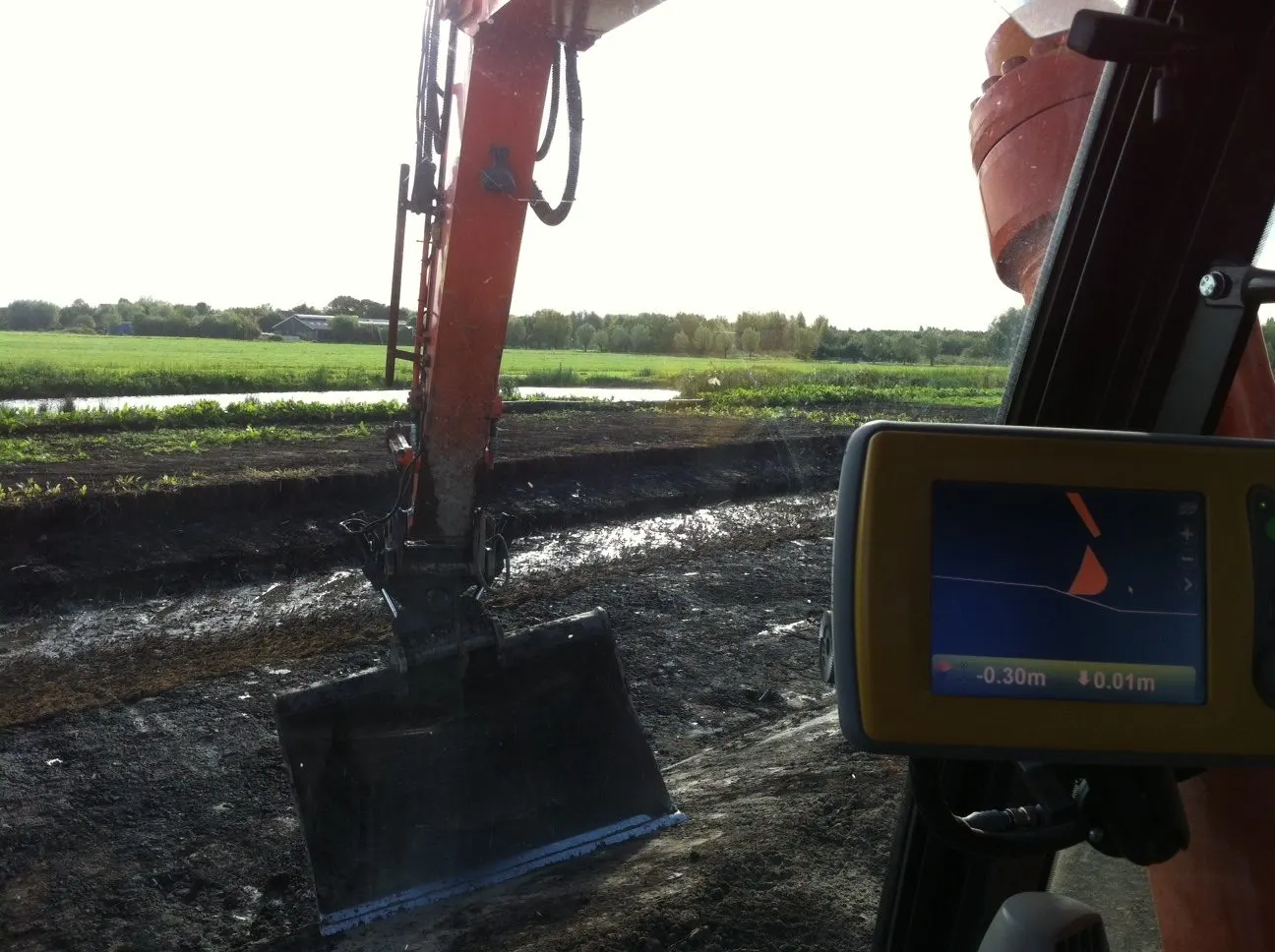 Zicht vanuit de cabine op het GPS-scherm en de bak die een sloot uitgraaft