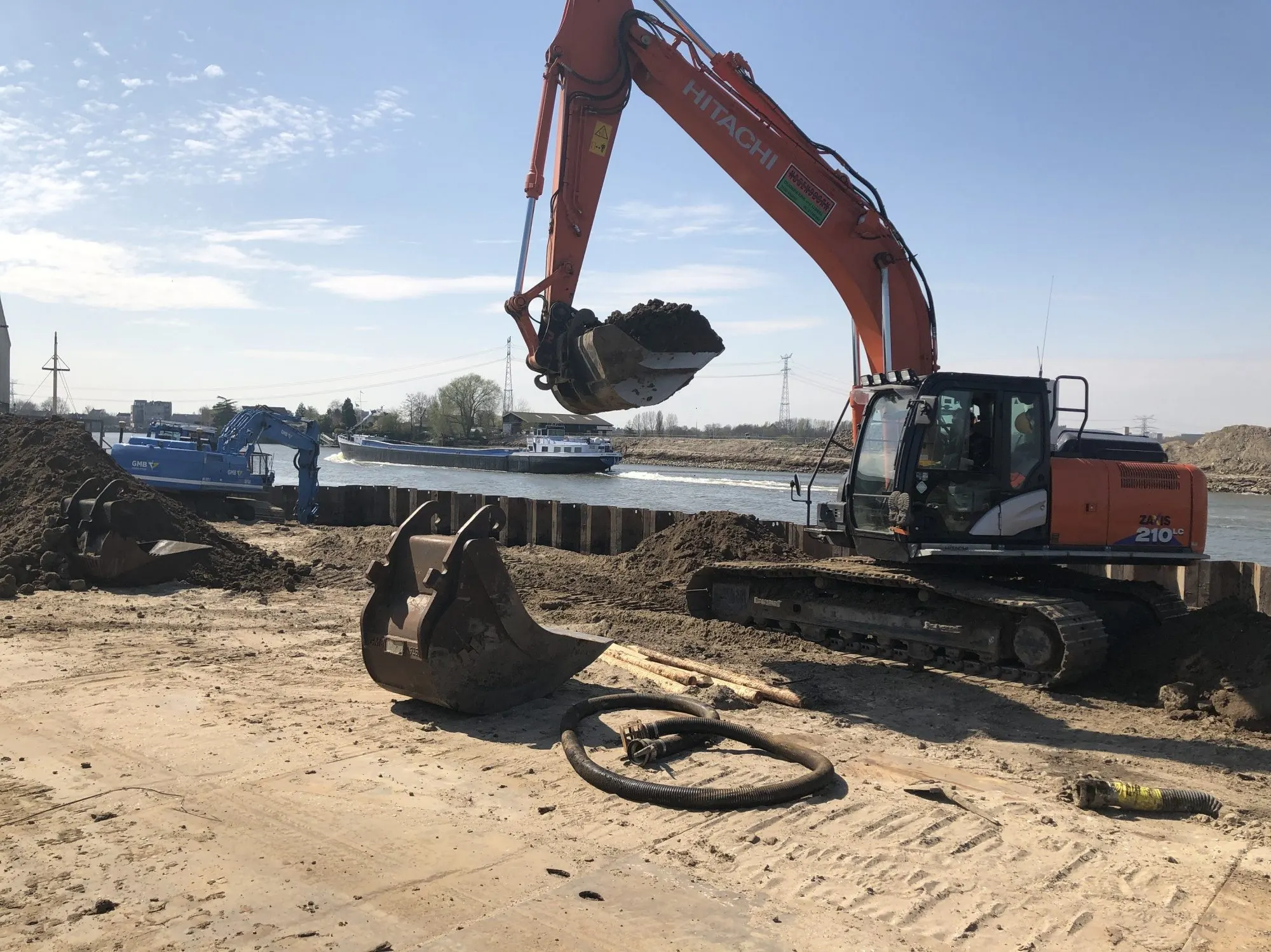 Hitachi ZX210 rupskraan aan de waterkant bij een damwand