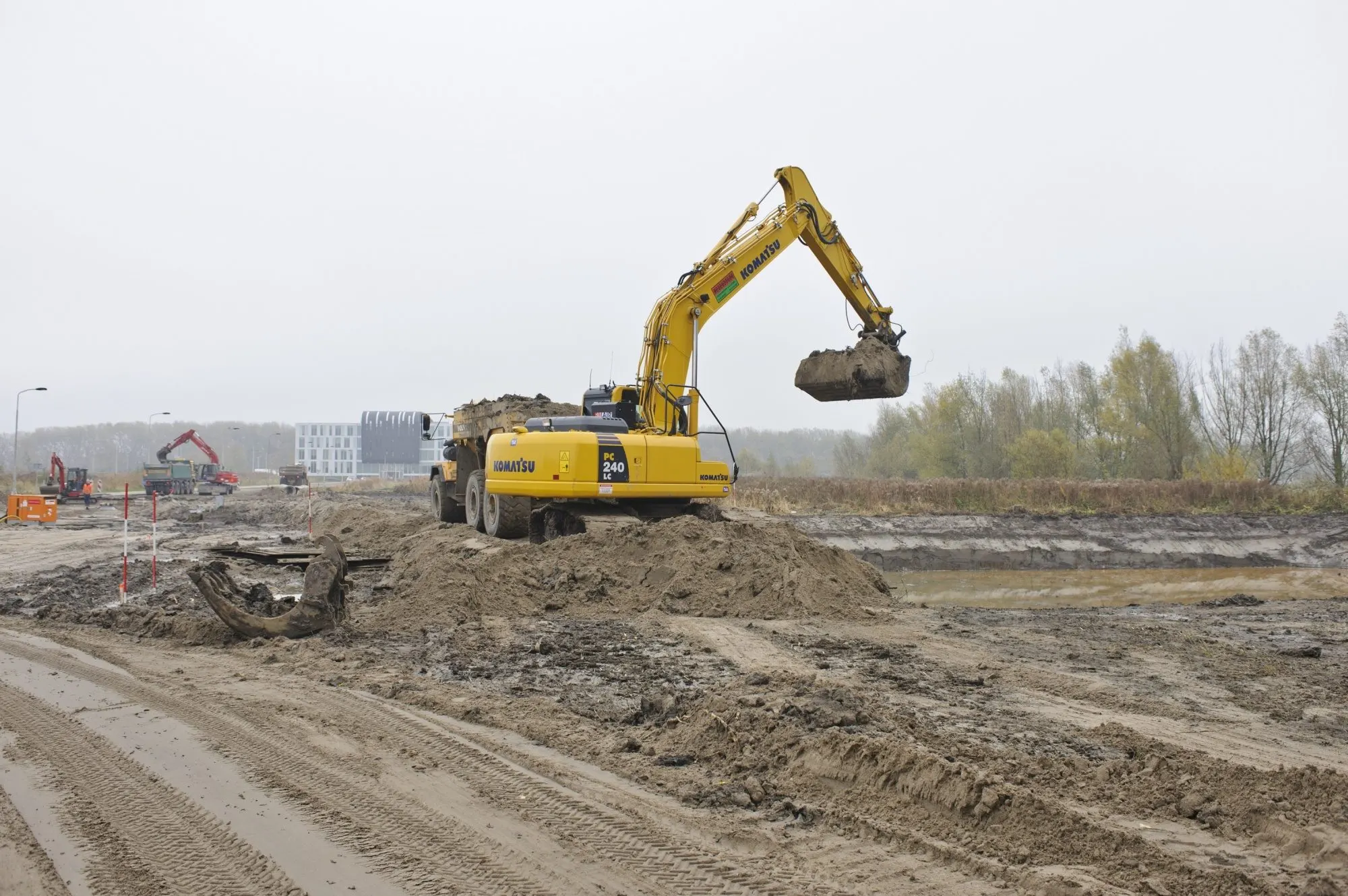 Komatsu rupskraan laadt een kipper op een zandterrein