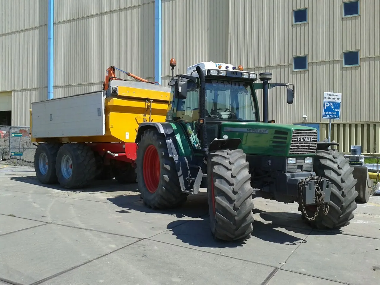 Fendt 514 tractor met gele kieper bij een bedrijfshal