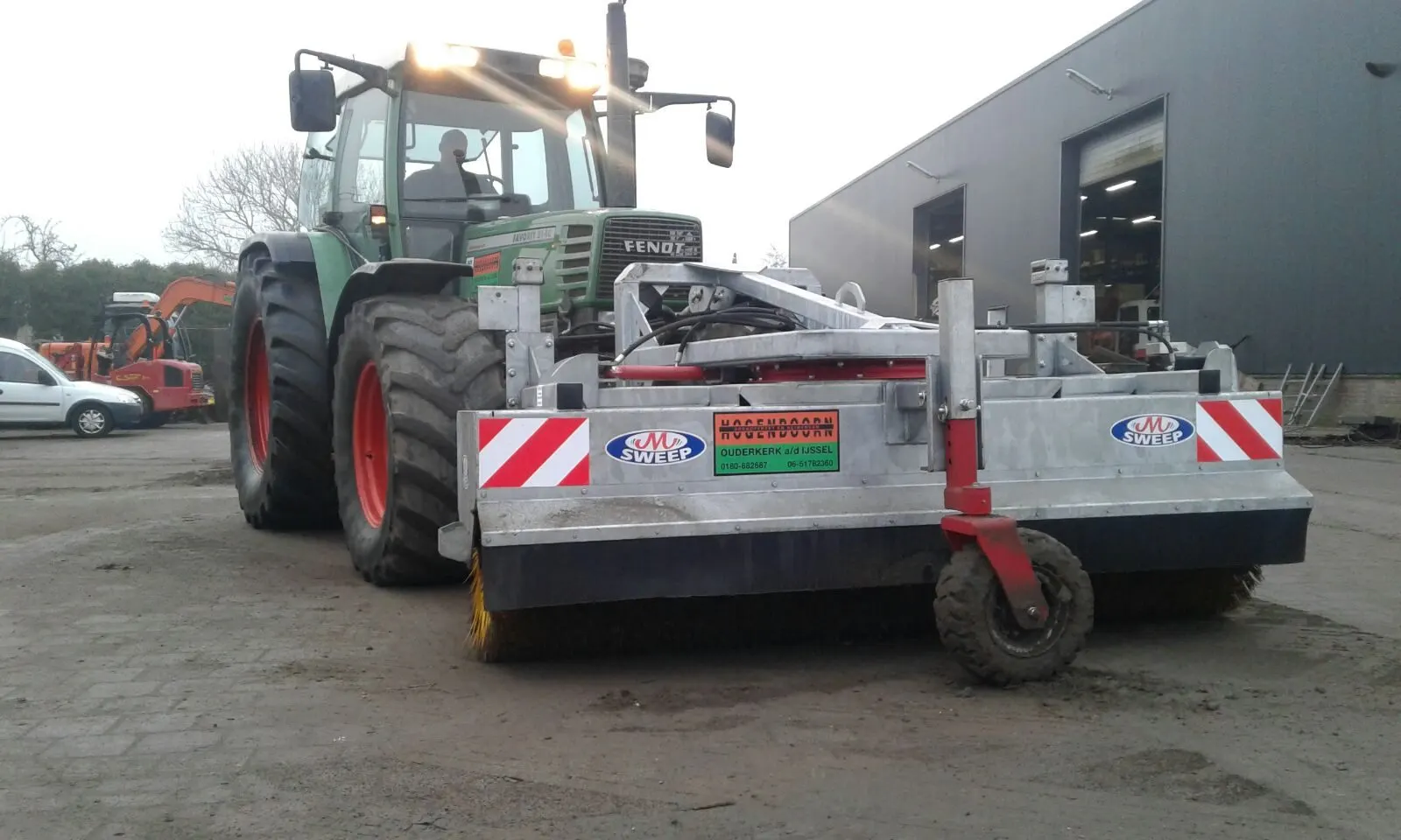 Fendt tractor met veegbezem voor het pand